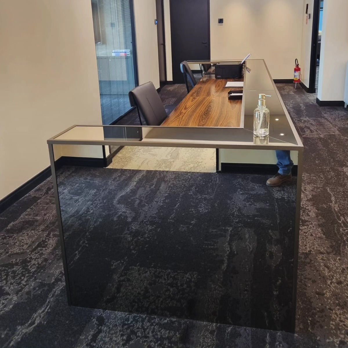 Mesa em L revestida em espelho bronze em recepção