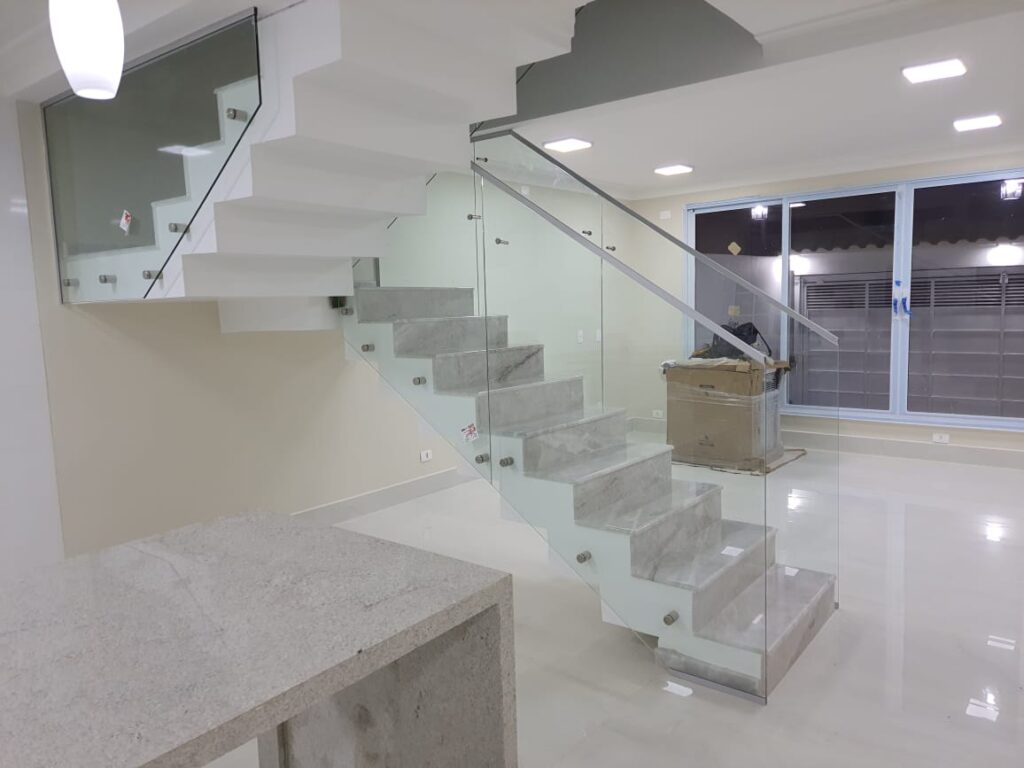 Escada residencial com guarda-corpo de vidro e ferragens em inox