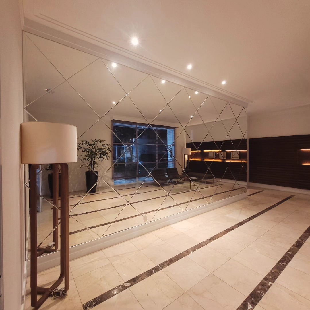 Hall com painel geométrico em espelho prata parede a parede
